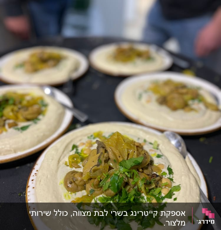 צלחות חומוס עם פטריות ועשבי תיבול מוגשות על שולחן